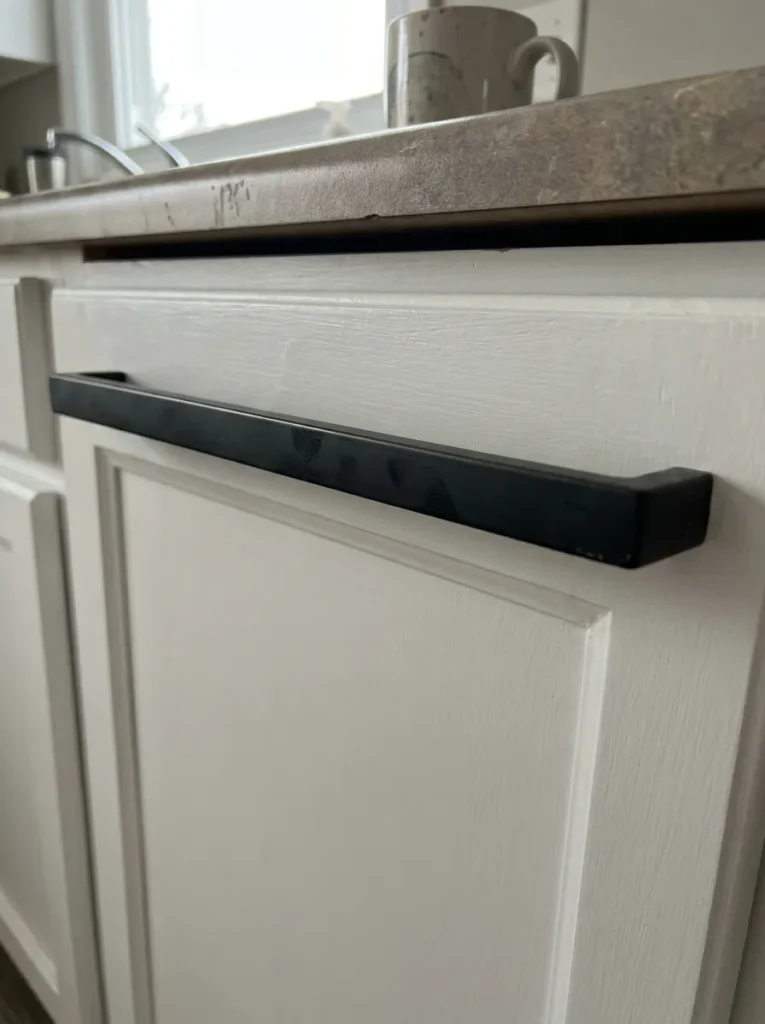 Sleek matte black bar pull installed on a white kitchen cabinet
