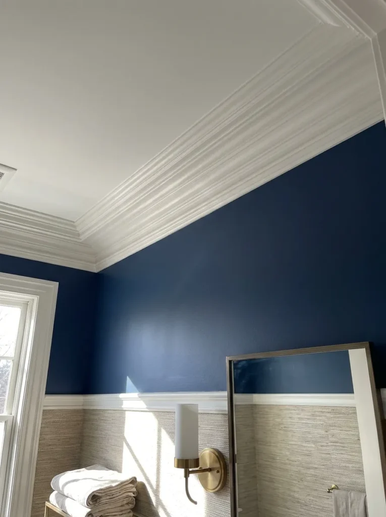 Thick white crown molding adding height to a navy blue powder room