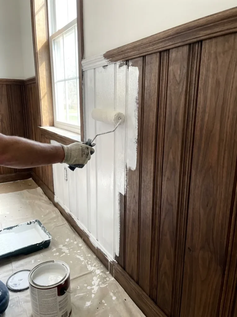 Applying white primer over dark wood wall paneling