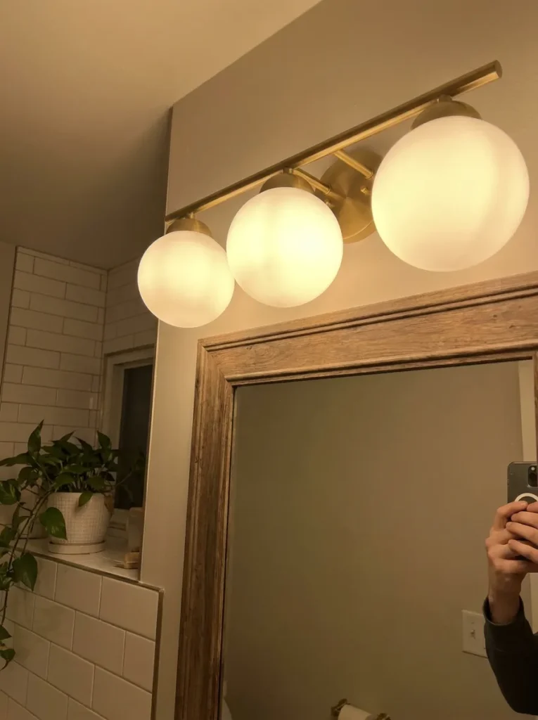 Modern brass vanity lighting replacing an old hollywood bulb strip