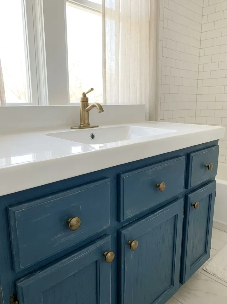 Dated oak bathroom vanity painted a rich dusty blue with brass knobs