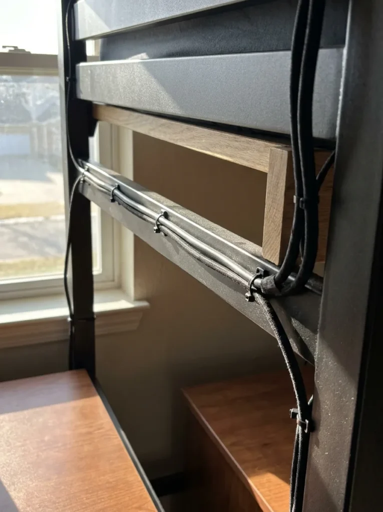 Cable management straps securing electrical cords behind an iron bed frame