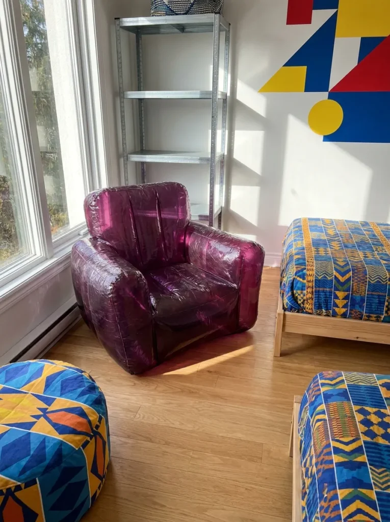 Translucent purple inflatable PVC blow up armchair sitting in a room corner