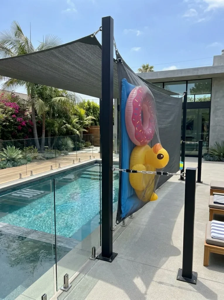Charcoal gray shade sail fabric pocket securing pool floats flat against fence posts