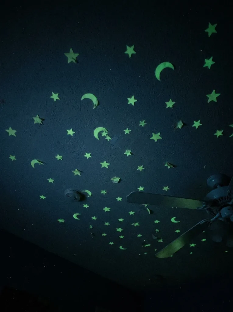 Glow in the dark star and moon stickers emitting a soft green phosphorescent light