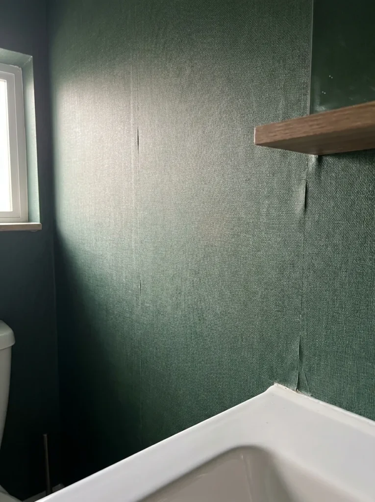 High close up of deep green linen textured peel and stick wallpaper